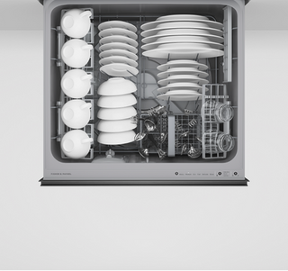Dishwasher with stacked white plates and bowls inside on a light gray background
