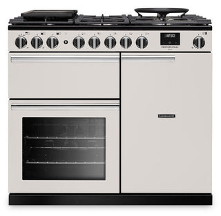 A classic dual-fuel range cooker in cream/off-white with black accents, featuring six control knobs, a digital display, a gas hob, and an oven window, shown on a plain white background.