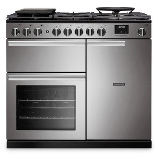 A stainless steel freestanding range cooker with six front control knobs, a glass oven door, and a black grate top, shown on a plain white background.