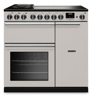 A freestanding range cooker in a light champagne-gold finish with black glass cooktop and oven windows, silver handles, and a row of control knobs on the front panel.